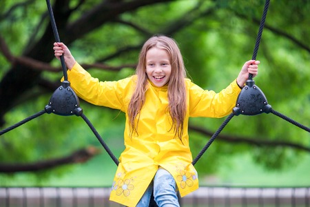Little girl playing at the playground in the park on rainy warm dayの写真素材