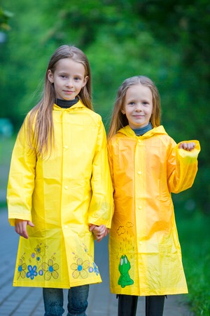Adorable little girls happy standing under the rain outdoorsの写真素材