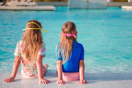 Cute toddler girls standing in shallow water at exotic beachの写真素材