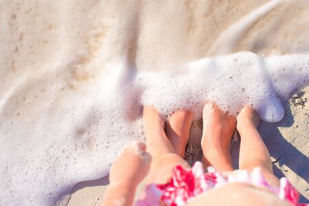 Closeup feet of mom and kid on white sand beachの写真素材