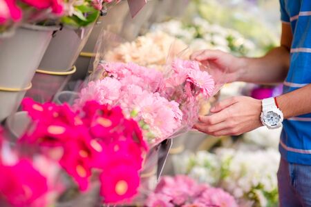 Beautiful young boyselecting flowers at flower marketの写真素材