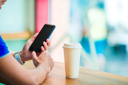 Closeup of male hands is holding cellphone with empty copy space screen for your advertising text message or promotional content. Closely of businessman search information in network with smart phoneの写真素材