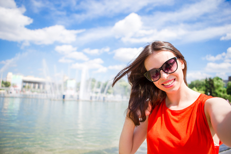 Young caucasian woman making photo by mobile phone outdoorsの写真素材