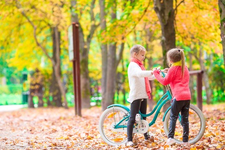 Adorable girl riding a bike at beautiful autumn dayの写真素材