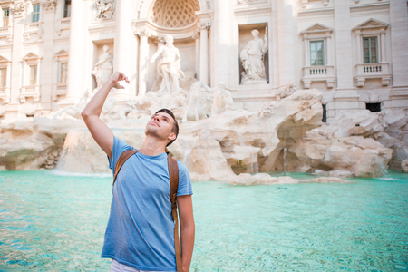 Young man near fountain Fontana di Trevi with coins in handsの写真素材