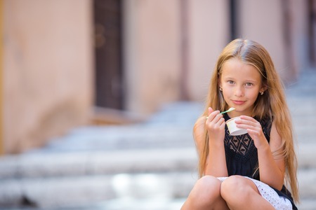 Adorable little girl eating ice-cream outdoors at summerの写真素材