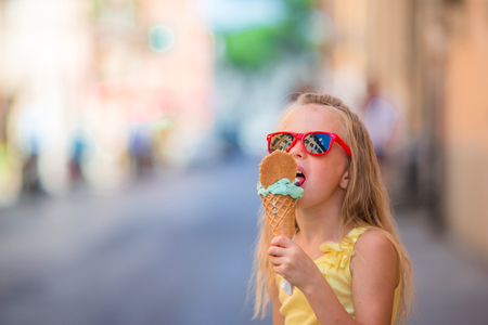 Adorable little girl eating ice-cream outdoors at summerの写真素材