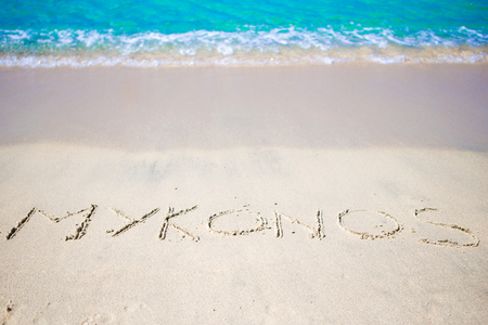 The word Mykonos in the sand against the seaの写真素材