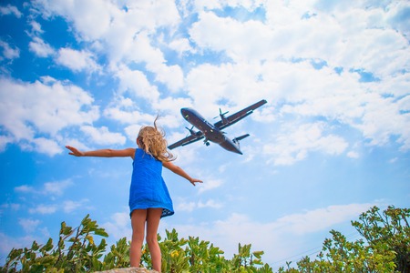 Little adorable girl looking at flying airplane