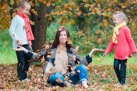 Portrait of cute girsl and happy mother in yellow autumn forest on a warm sunny dayの写真素材