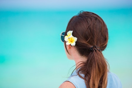 Young beautiful woman during tropical beach vacation. Enjoy suumer vacation alone on the beach at Africa with frangipani flowers in her hairの写真素材