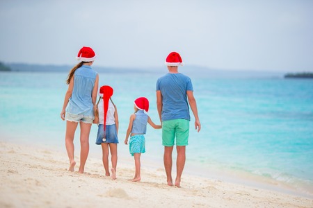 Happy family of four in Christmas Hats during tropical vacationの写真素材