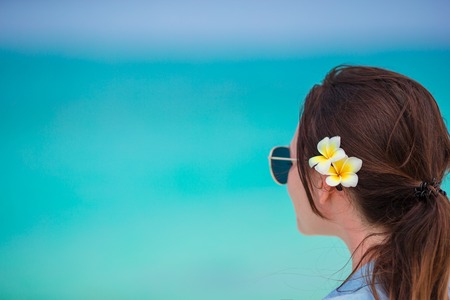 Young beautiful woman during tropical beach vacation. Enjoy suumer vacation alone on the beach at Africa with frangipani flowers in her hairの写真素材