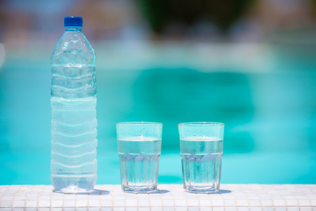 Glasses of waters and bottle on the edge of infinity swimming poolの写真素材