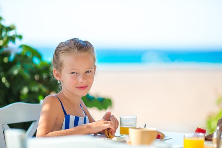 Adorable little girl having breakfast at restaurantの写真素材