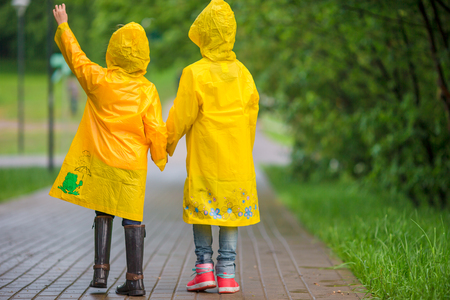 Adorable little girls happy standing under the rain outdoorsの写真素材