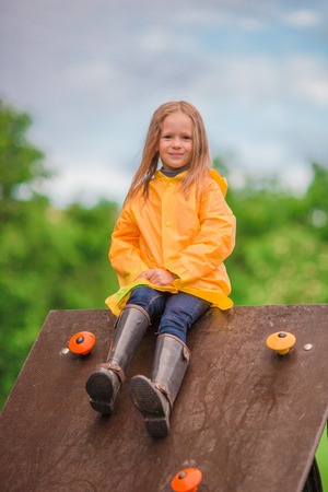 Little girl playing at the playground in the park on rainy warm dayの写真素材