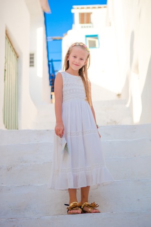 Cute girl in blue dresses having fun outdoors on Mykonos streetsの写真素材