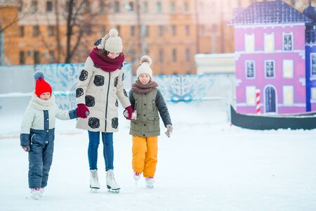 Smiling young mother and her cute little daughter ice skating together