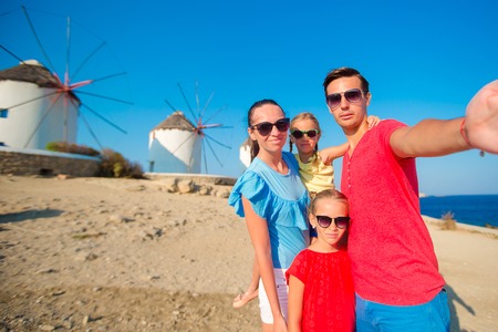 Family taking selfie with a stick in front of windmills at popular tourist area on Mykonos island, Greeceの写真素材