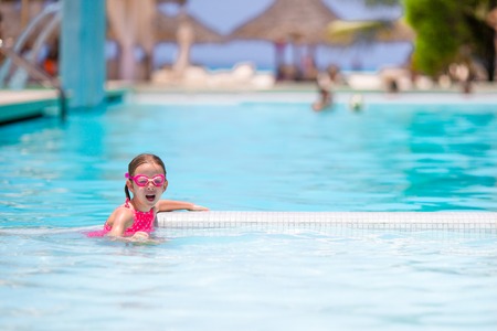 Little happy adorable girl in outdoor swimming pool