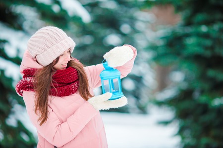 Happy girl holding Christmas candlelight outdoors on beautiful winter snow dayの写真素材