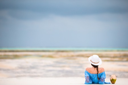 Back view of young beautiful woman on the beach during low tideの写真素材
