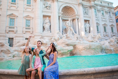 Happy family trowing coins at Trevi Fountain, Rome, for good luck. Little girls and parents making a wish to come back.の写真素材