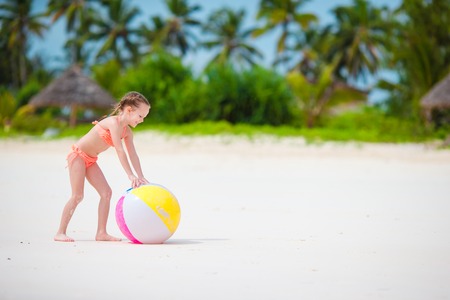Cute little girl playing with ball on beach, kids summer sport outdoorsの写真素材