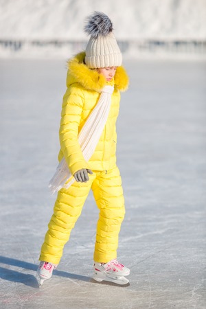 Adorable little girl skating on the ice rink outdoorsの写真素材