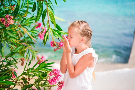 Little adorable girl smelling colorful flowers outdoors on greek streetsの写真素材