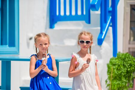 Happy little girls eating ice-cream in openair cafe in old streetの写真素材