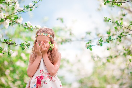 Adorable little girl enjoying smell in a flowering cherry spring gardenの写真素材