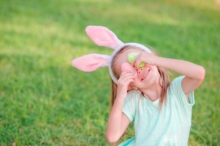 Adorable little girl on Easter holiday sitting on the grassの写真素材