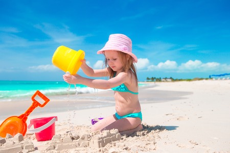 Adorable little girl playing with beach toys on white sandy beachの写真素材