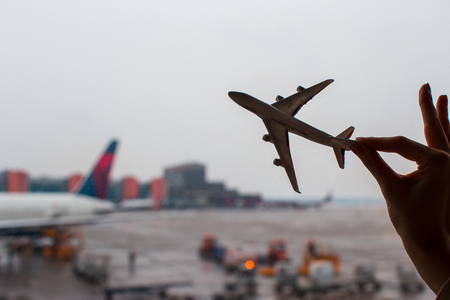 Closeup hand holding an airplane model at airportの写真素材
