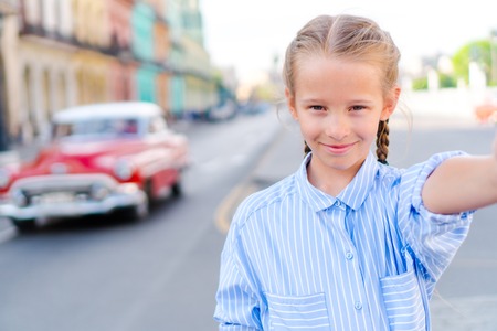 Little girl taking selfie in popular area in Old Havana, Cuba. Portrait of kid outdoors on a street of Havanaの写真素材