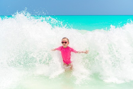 Adorable little girl at beach having a lot of fun in waterの写真素材
