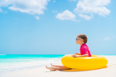 Adorable little girl with inflatable rubber circle have fun on the beachの写真素材