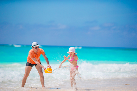 Little girl and happy dad having fun during beach vacationの写真素材