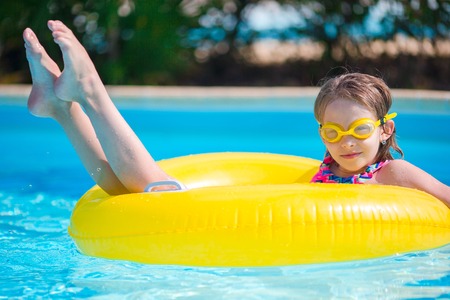Little girl with inflatable rubber circle having fun in outdoor swimming poolの写真素材