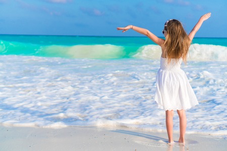 Adorable happy little girl on white beachの写真素材