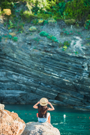Young girl in a cove on a rock in the Cinque Terre Reserve. Stunning nature and fresh airの写真素材