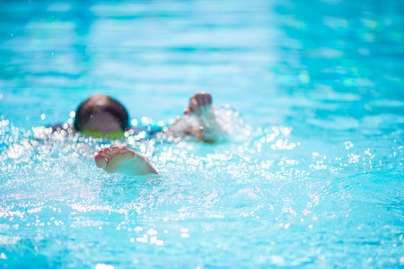 Happy little girl having fun in outdoor swimming pool