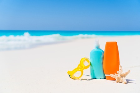 Suncream bottles, goggles, starfish on white sand beach background oceanの写真素材
