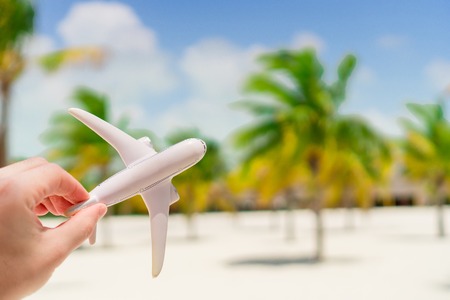 Small white miniature of an airplane on background of exotic beach and palmtreesの写真素材