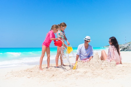 Family of four making sand castle on their beach vacationの写真素材