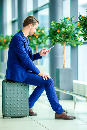 Young man with smart phone in airport. Caucasian man with cellphone at the airport while waiting for boardingの写真素材