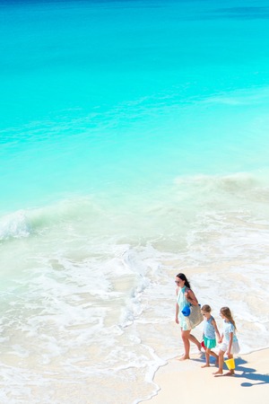 Adorable little girls and young mother on white beach. View to the family on the beach and ocean from aboveの写真素材