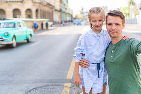 Family of dad and little girl taking selfie in popular area in Old Havana, Cuba. Little kid and young father outdoors on a street of Havanaの写真素材